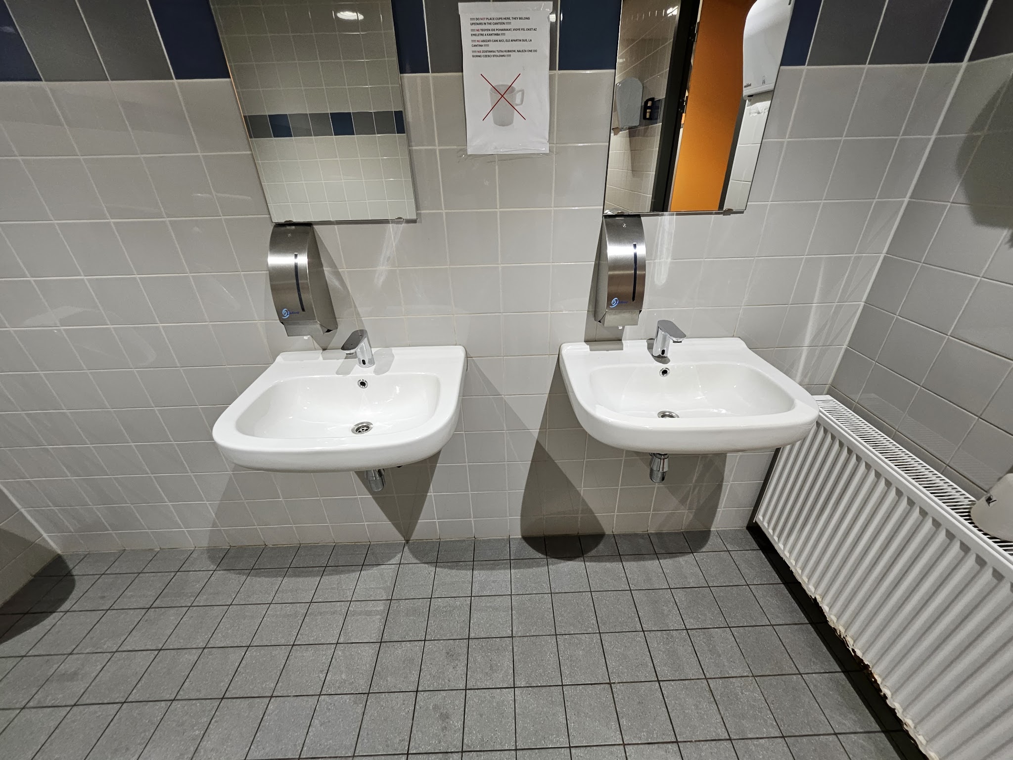Twee wastafels met spiegels boven een schone tegelvloer